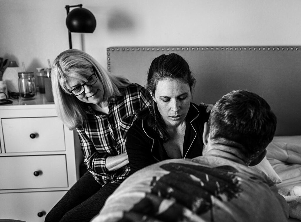 A woman in labor at home is supported by her mother and husband. 